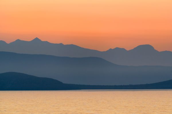 Orange sunrise over purple mountains near the ocean