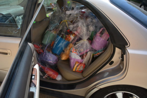 Cellophane-wrapped Easter baskets filled with candy and toys in the back seat of a car with the door open