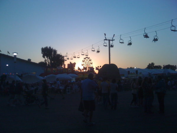 OC Fair Ferris wheel and skyride silhouetted against the sunset as fairgoers walk by, 2013