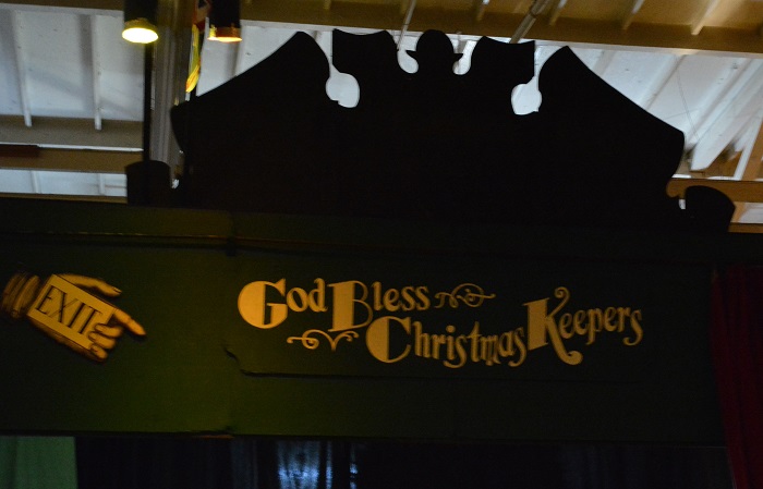 Green "Exit" sign with gold letters, "God bless the Christmas keepers"