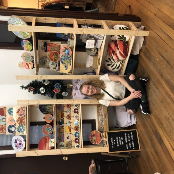 Melissa near shelves of her embroidery kits in a small shop