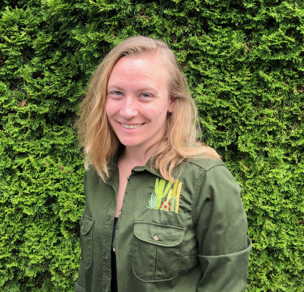Fiberr artist Melissa Galbraith, in a green khaki shirt, near a background of trees