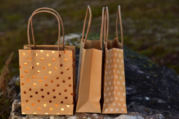 three small brown-paper shopping bags with handles sprinkled with gold stars