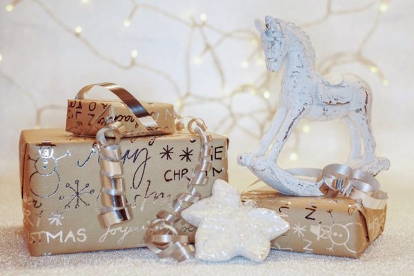 Gifts wrapped in paper printed with "Merry Christmas" next to a white star ornament on the floow