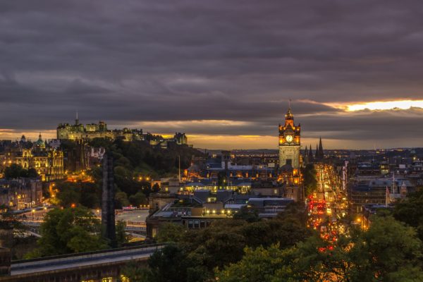 Sunset and night sky over lighted buildings in city of Edinburgh