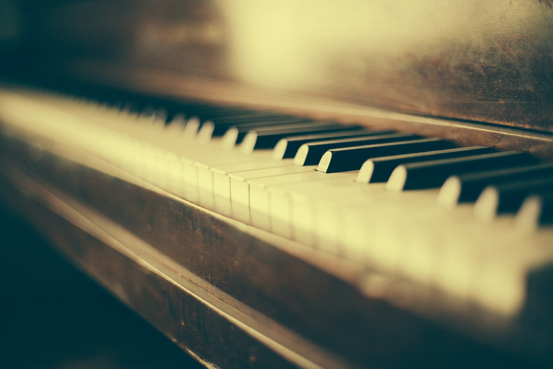 Older baby grand piano with closeup on yellowed keys 