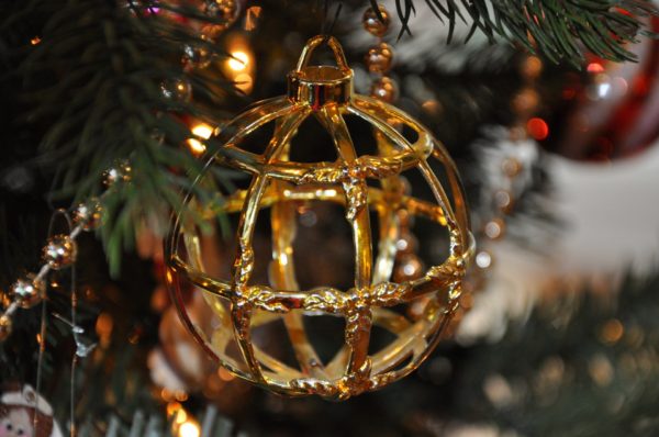 Lacy gold Christmas ornament on tree branch
