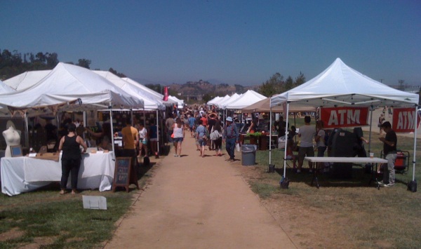Long line of vendors' booths at Renegade Craft Fair in Los Angeles State Historic Park, on either side of a dirt pathway