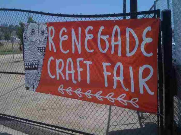 Orange "Renegade Craft Fair" sign with white owl on chain-link outdoor fence near state park