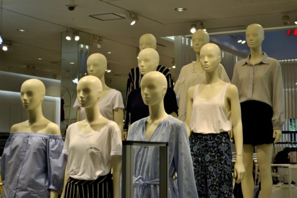 six department store mannequins in slender blouses, skirts and dresses