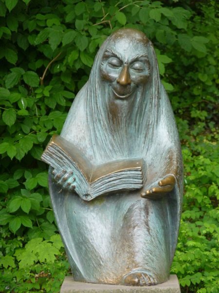 Stone staue of a magical wizrd reading from a book