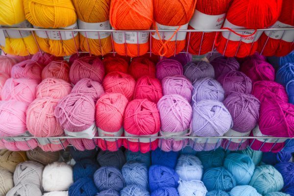 Skiens of 3-ply yarn in rainbow colors from pink to orange to gold on a store shelf