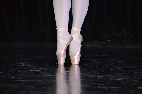 A dancer's feet as she stands en pointe in pink satin ballet shoes