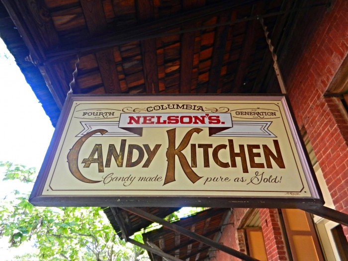 Large yellow sign advertises "Nelson's Candy Kitchen" as it hangs above a walkway