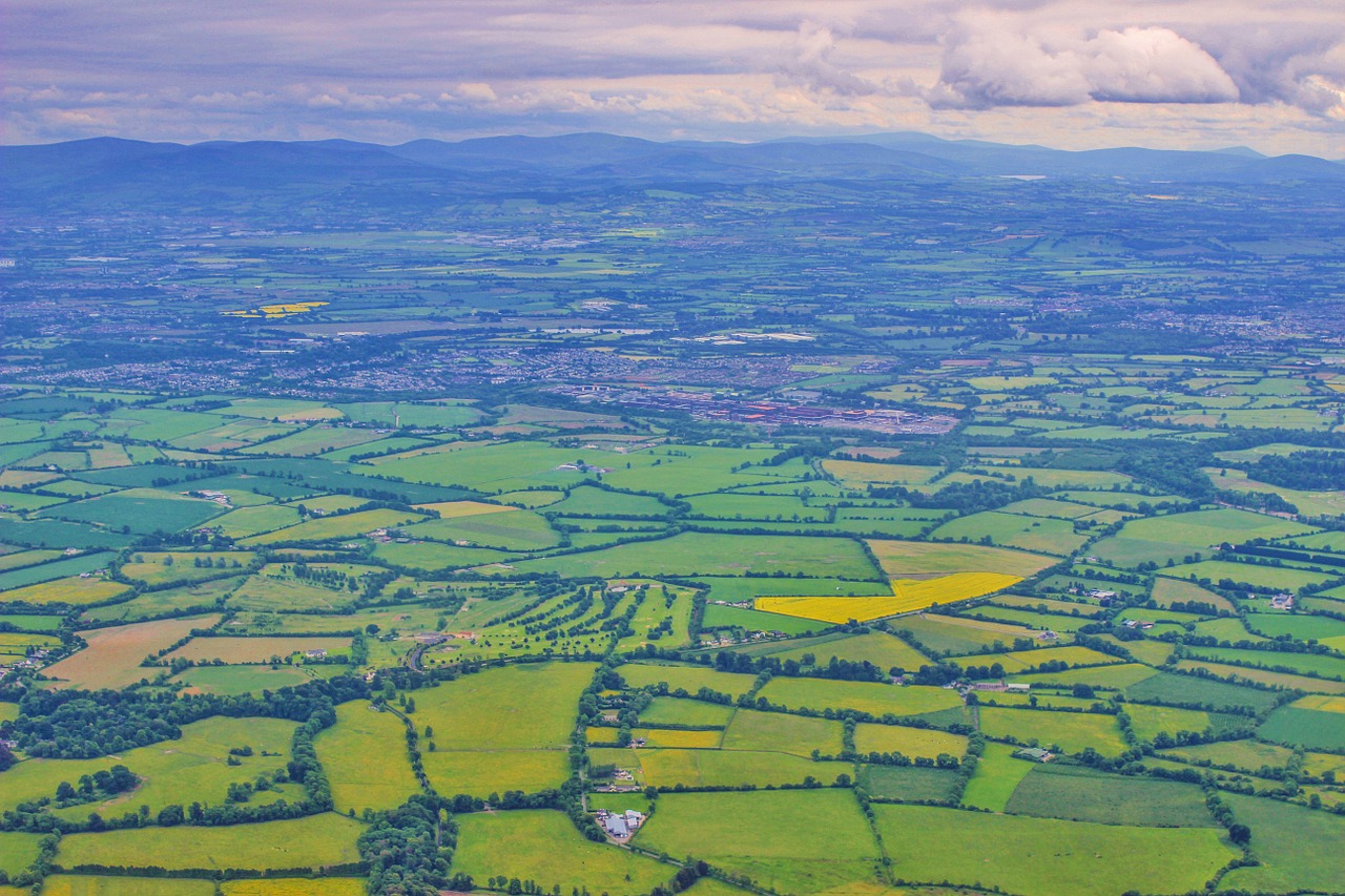 Aerial view of Irish green fields with blue mountains and clouds in the distance