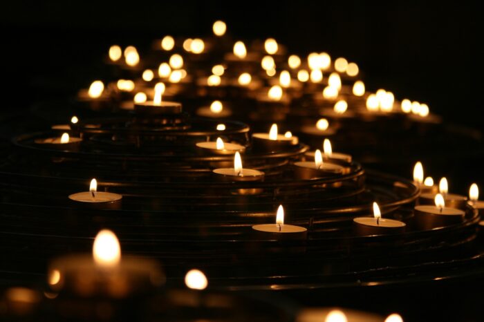 Multiple candles shine through a dark background