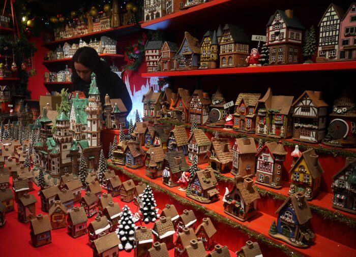 Woman stands among shelves of gingerbread houses at European Christmas market
