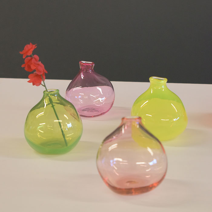 Four translucent glass vases: light green with a red flower; light orange, lemon yellow and rose pink.