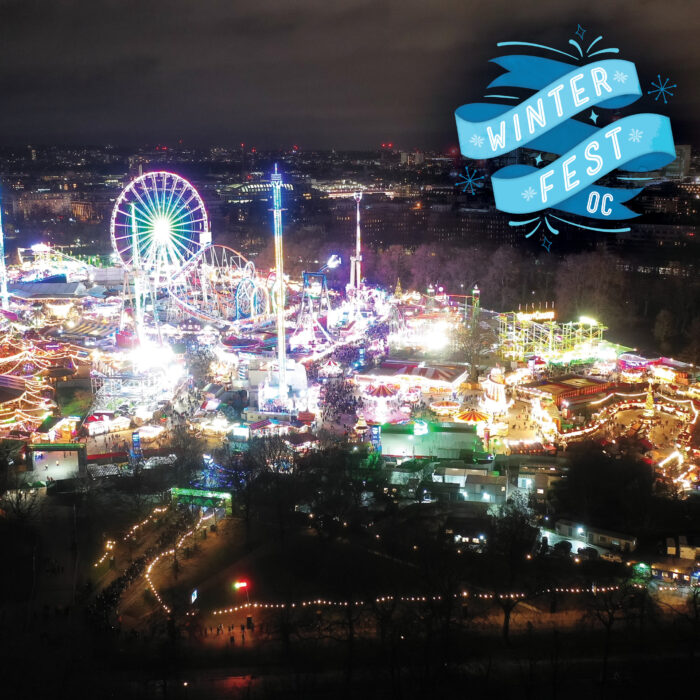 Night view of OC Fair lit up for WinterFest OC with lighted Ferris wheel and "Winter Fest OC" on a blue banner