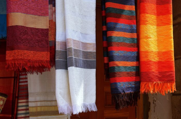 Four woven striped African blankets hang on a rack