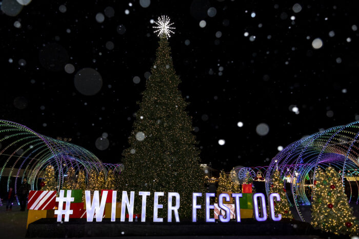 Lit Christmas tree against night sky with "OC Winter Fest" in white lettering