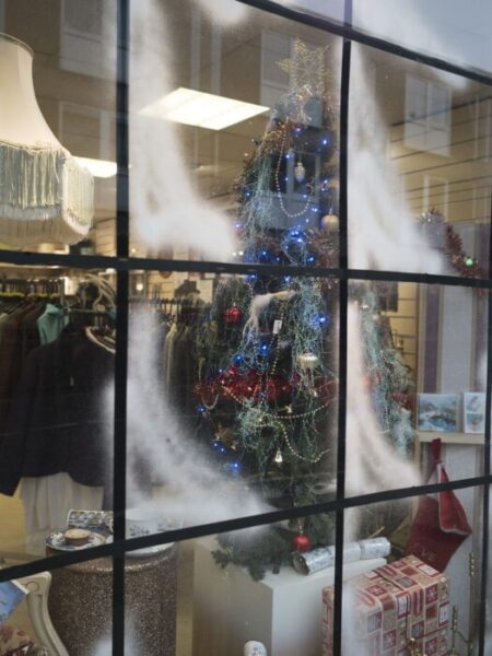 Multipaned shop window with white "snow' decorations and trimmed Christmas tree inside.