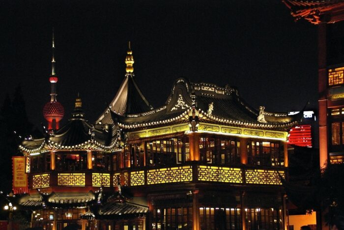 Chinese pagoda with red pillars and awash in gold light against a night sky