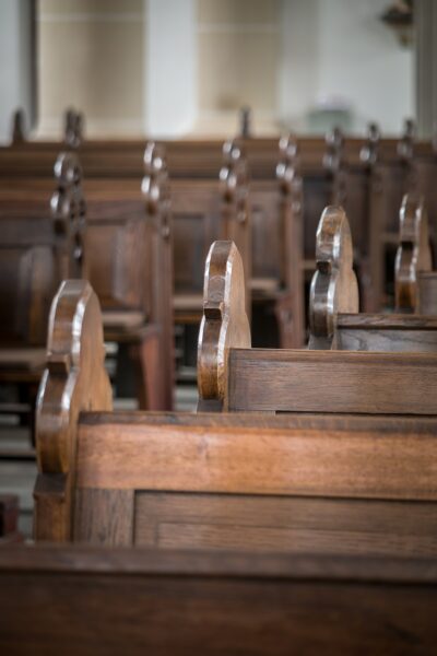 Row of wooden church pews across an aisle from another row.