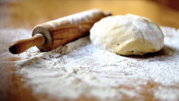 Dough and rolling pin on a floured surface.