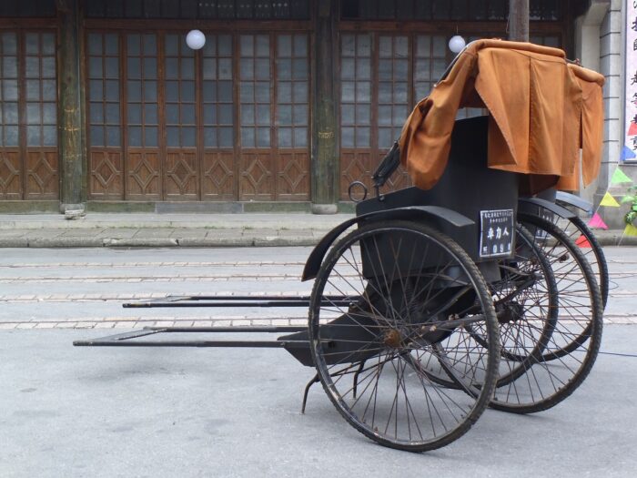 Rickshaw sits outside wood-paneled house in Old Shanghai.