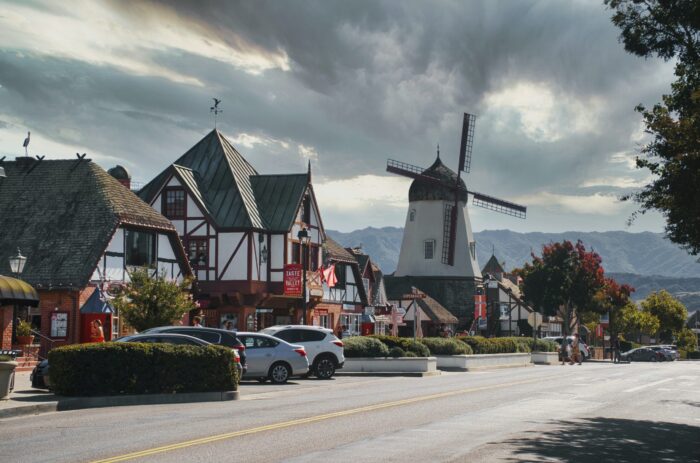 Solvang's main street, with Danish shops and windmill against cloudy sky.