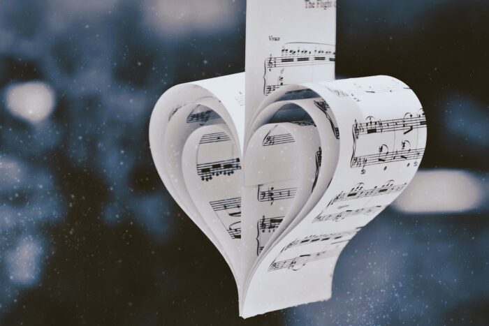 Paper heart shaped from a musical score and hanging like a Christmas ornament.
