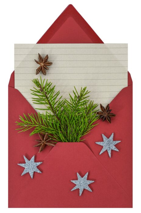 Christmas stationery in a red envelope sprinkled with silver snowflakes with a sprig of pine tucked inside.