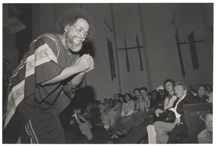 Black-and-white photo of Reverend Cecil Williams, in the 1960s, preaching to a congregation.