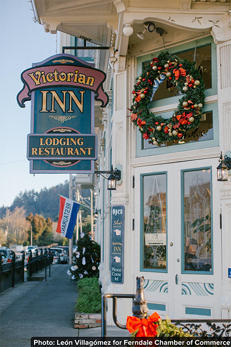 Victorian Inn sign on a white building with bay windows and a Christmas wreath.