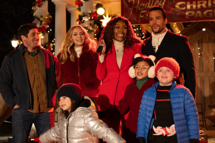 Jackie, Charlotte, Rob, Valentino, Beatrix, Grant and Dora stand together in front of a sign that says "Christmas Pageant"