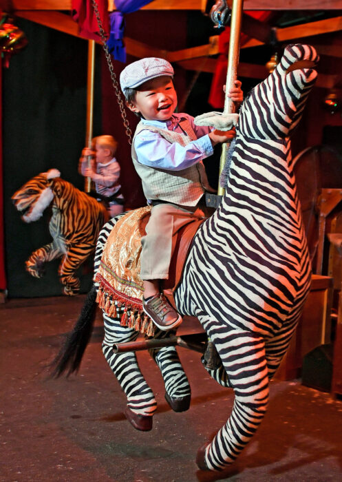 Young adventurers ride a zebra and a tiger on the Dickens Fair's hand-powered "Adventure Carousel".
