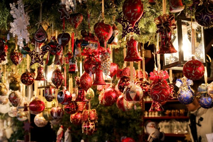 Red glass Christmas ornaments hang from the rafters in European Christmas market
