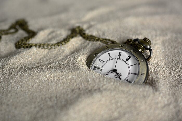 Antique pocket watch half-hidden in sand