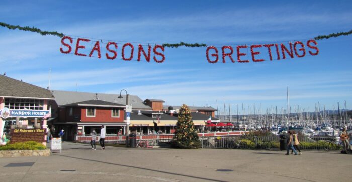 "Seasons Greetings" red lettering and garland over Old Fisherman's Wharf in Monterey
