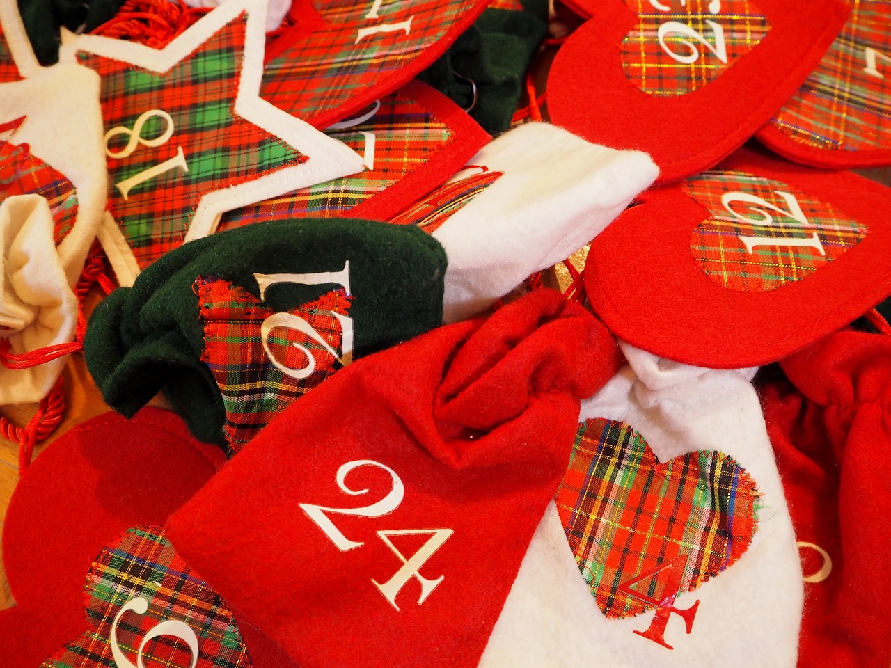 Fabric advent calendar with individual gift bags made of red and plaid fabric, each with a date on them. "24" is front and center.