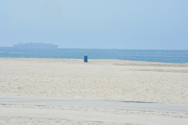 Beach in Long Beach, with a ship out on the water and a trash can on the horizon.
