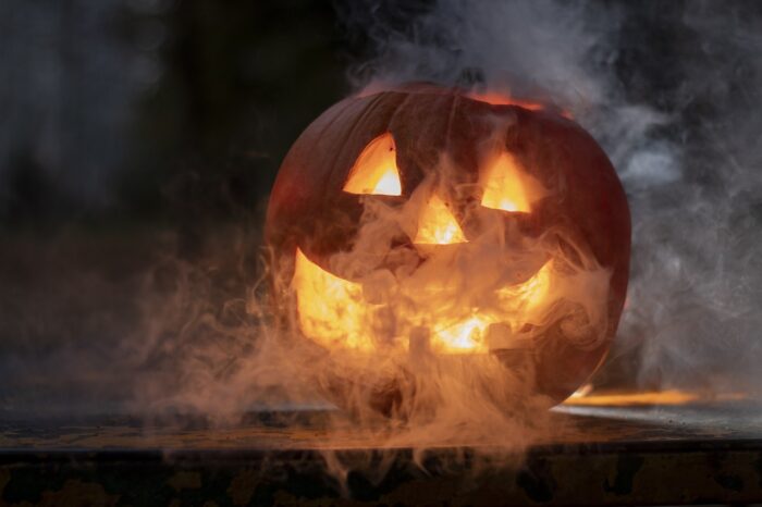 Grinning lighted jack-o-lantern in a haze of smoke.