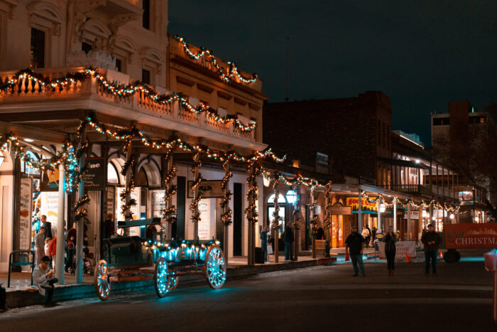 Facades of historic buildings decorated with garlands of Christmas lights.