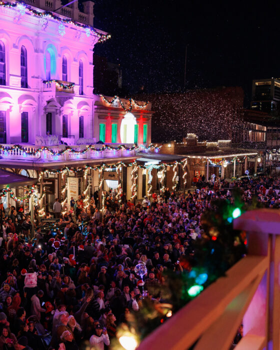 Crowd gathers vbeneath the lighted balconies of Old Sacramento historic building.