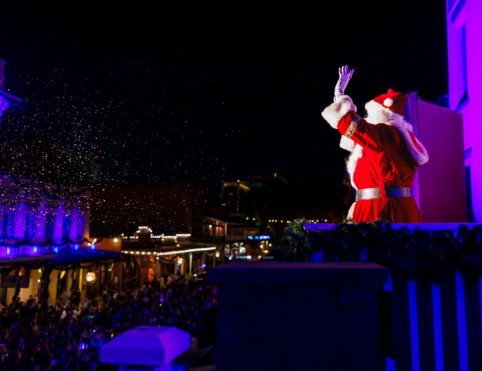 Santa waves to crowd from darkened balcony of Old Sacramento historic building.