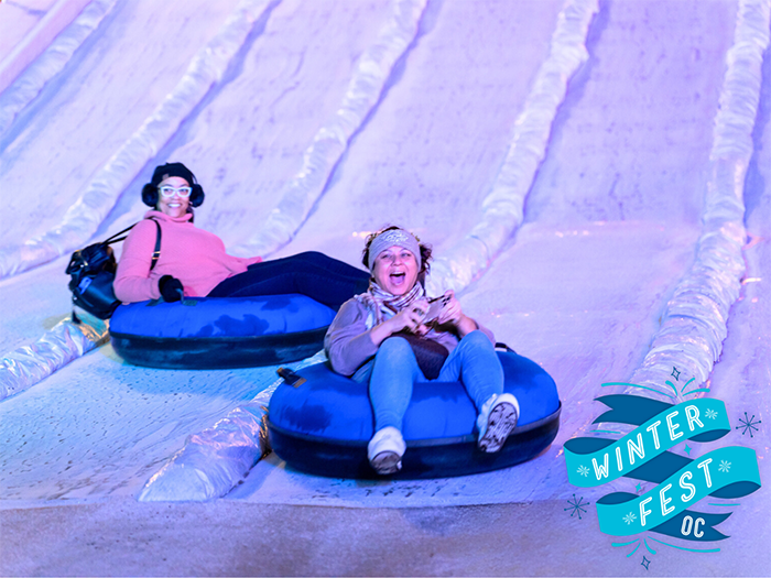 Laughing children ice tube down a snowy slope.