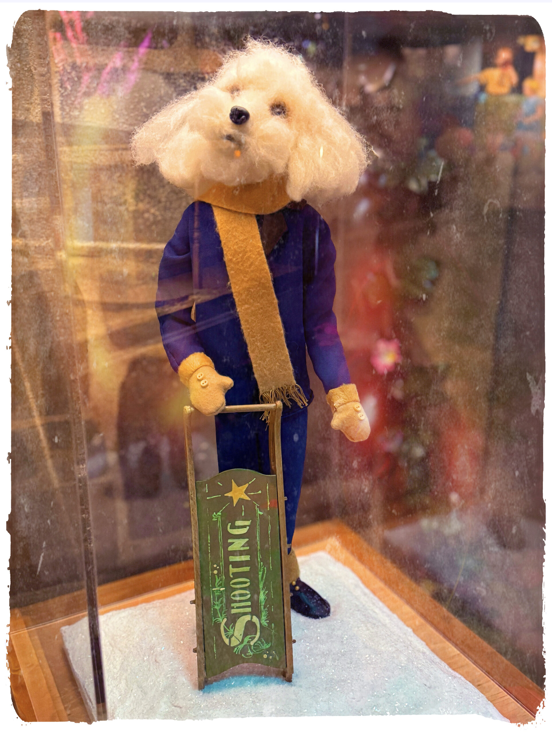 Small stuffed dog in a DIckensian jacket with a sled