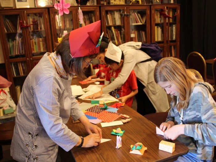 Children fold origami squares during "Krazy Krafts Day"