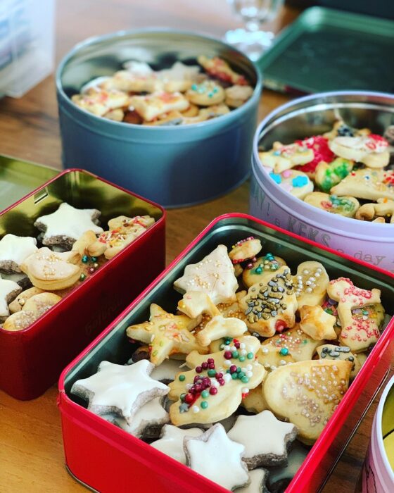 Metal tins of Christmas cookies, including star-shaped sugar cookies and cutout trees with sprinkles